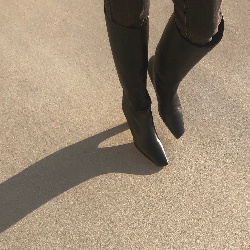 Neil J Rodgers black Meg knee high boots with a pointed square toe made from soft Italian nappa leather paired with black skinny denim.