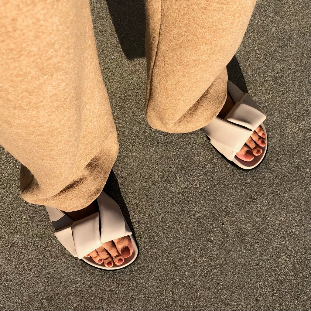Neil J Rodgers off-white Obi slide sandal with padded leather straps, comfortable flat footbed and lightweight thick black sole styled with camel cashmere pants.