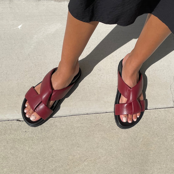 Neil J Rodgers burgundy Obi two sandal with a two-strap style made with padded leather straps, a comfortable flat footbed and lightweight thick black sole worn with a black skirt.