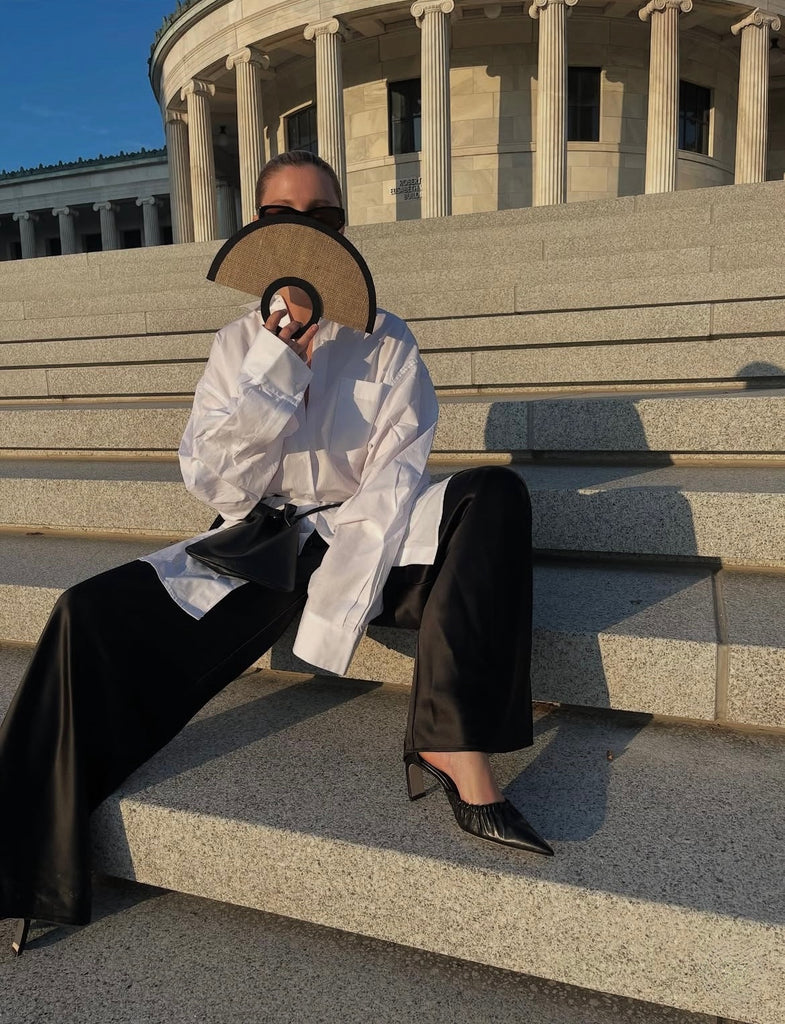 MODEL ON ROMAN STEPS IN CHIC BLACK AND WHITE OUTIFT WEARING MID HEEL ROUCHED DORSAY PUMPS IN BLACK NAPPA LEATHER