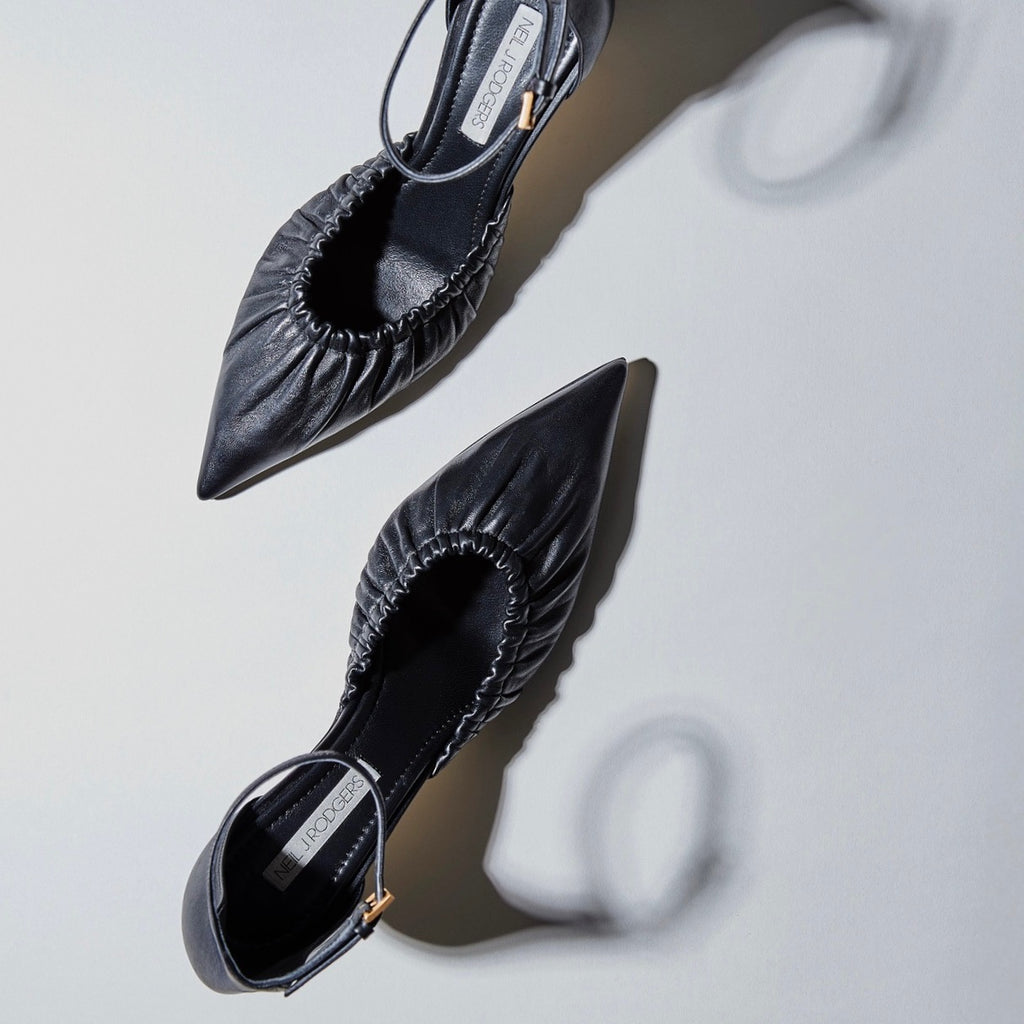 WOMENS ROUCHED LEATHER D'ORSAY PUMPS IN BLACK LEATHER IN A STYLIZED MINIMAL STUDIO SETTING