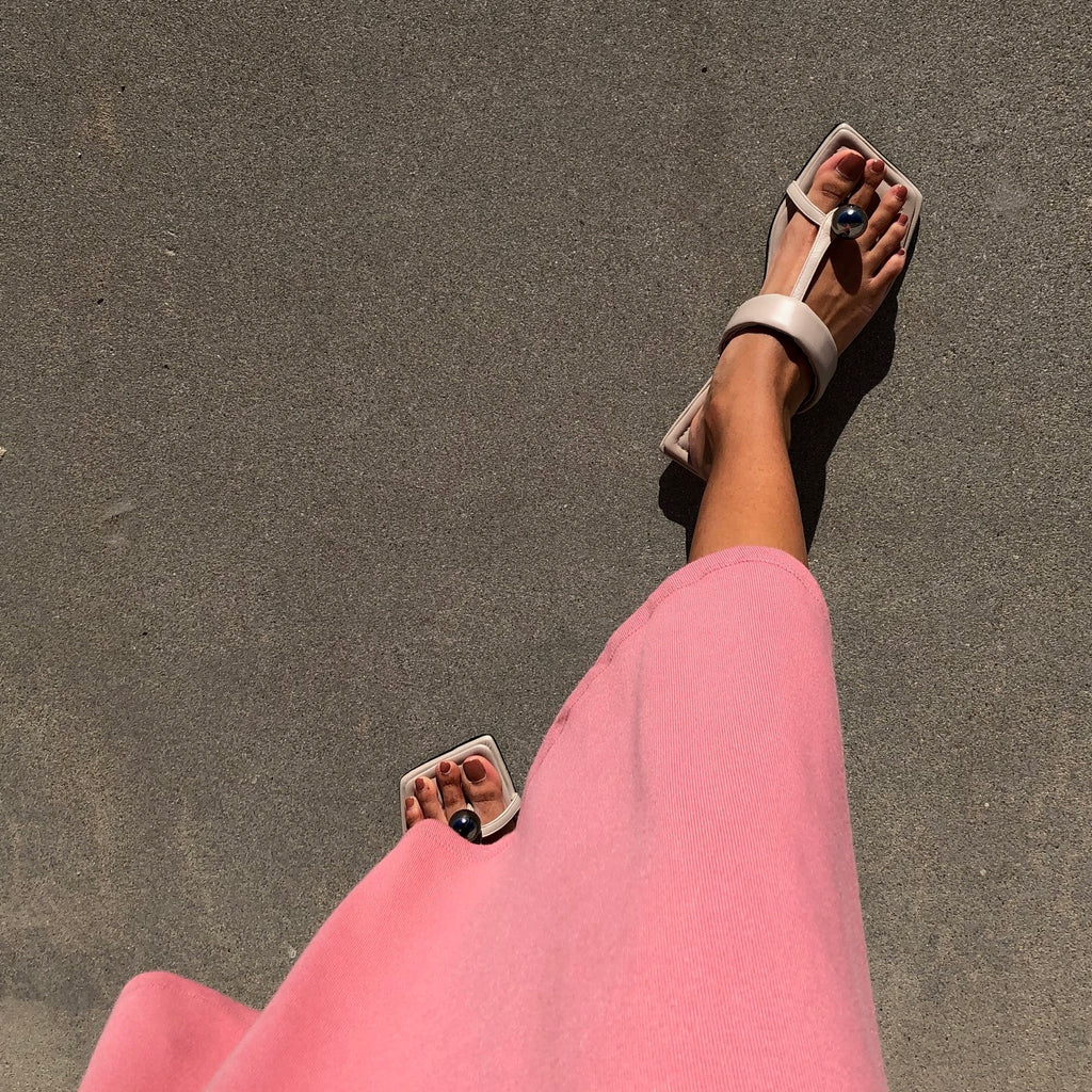 Neil J Rodgers off-white Samira sandal with a flat footbed, minimal leather straps and silver bead embellishment paired with a pink midi dress.