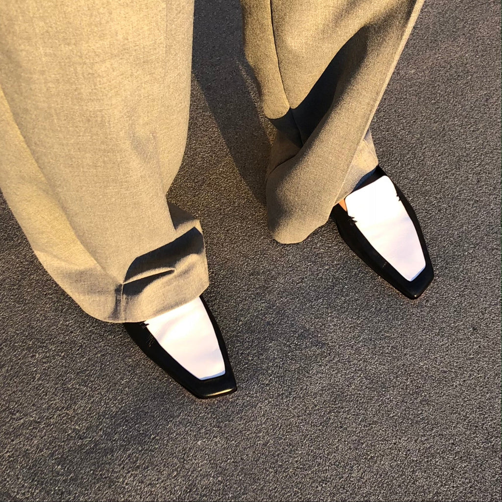 Neil J Rodgers black and white Liscia loafer with a pointed square toe and minimal stitching in soft Italian nappa leather paired with oversized grey pants.