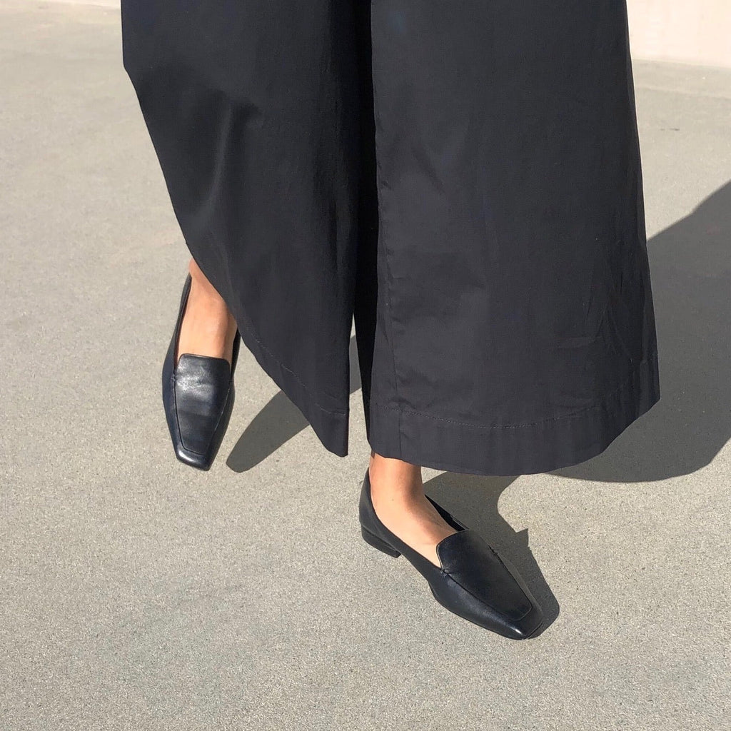 Neil J Rodgers black Liscia loafer with a pointed square toe and minimal stitching in soft Italian nappa leather paired with wide leg, lightweight black pants.