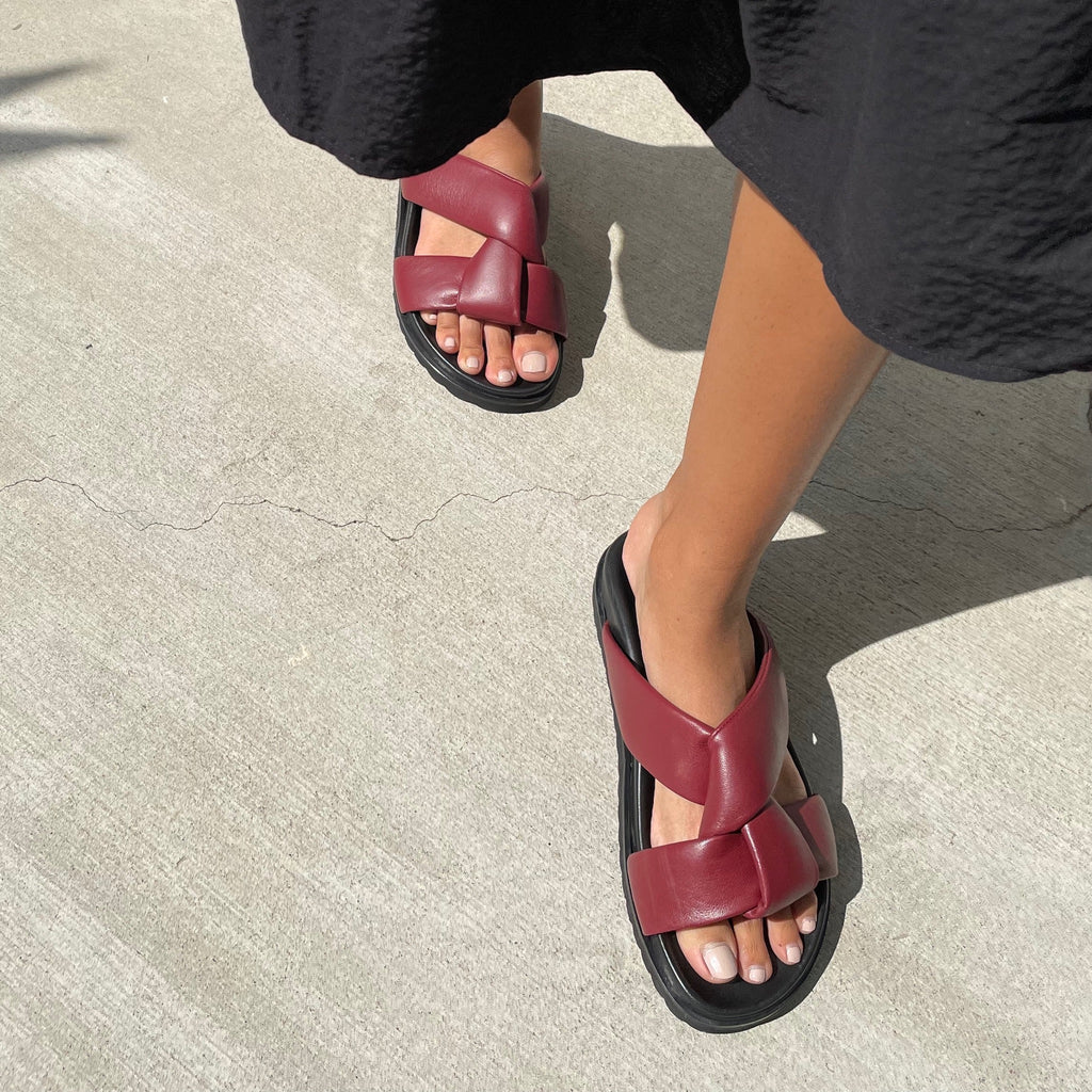 Neil J Rodgers burgundy Obi two sandal with a two-strap style made with padded leather straps, a comfortable flat footbed and lightweight thick black sole worn with a black skirt.
