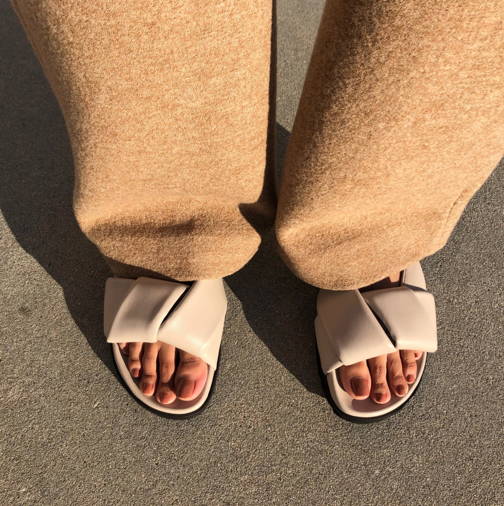 Neil J Rodgers off-white Obi slide sandal with padded leather straps, comfortable flat footbed and lightweight thick black sole styled with camel cashmere pants.